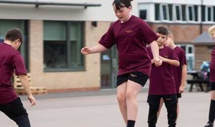 Female student jumping in playground during PE lesson