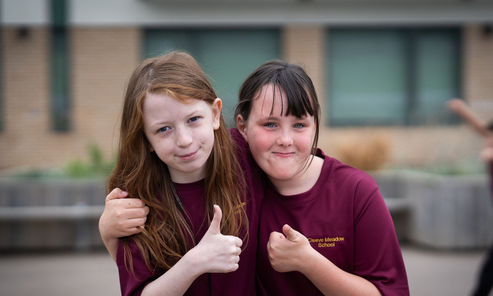 Two female studnets looking at camera doing a thumbs up
