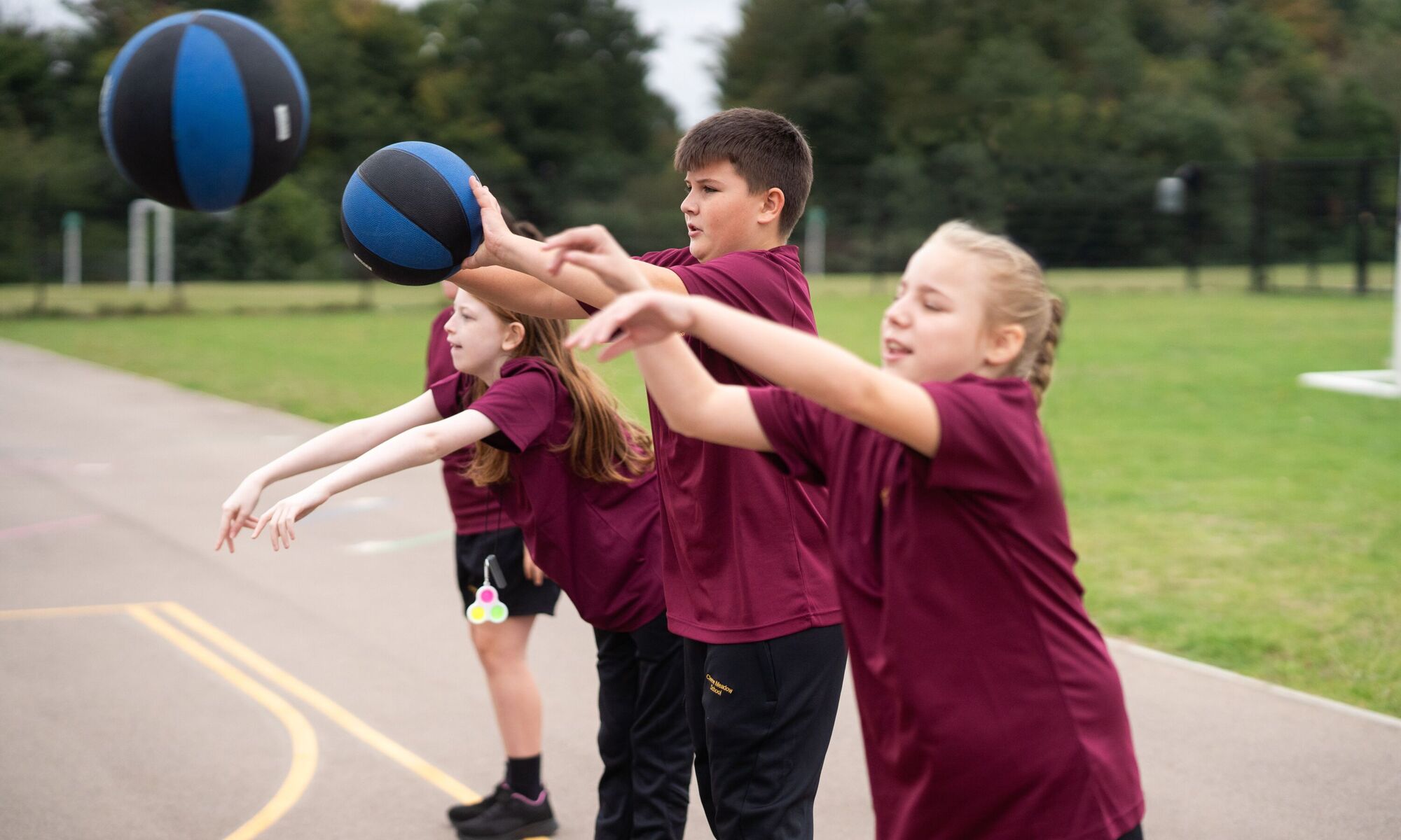 Boys and girls throwing basketballs in playground during pe lesson