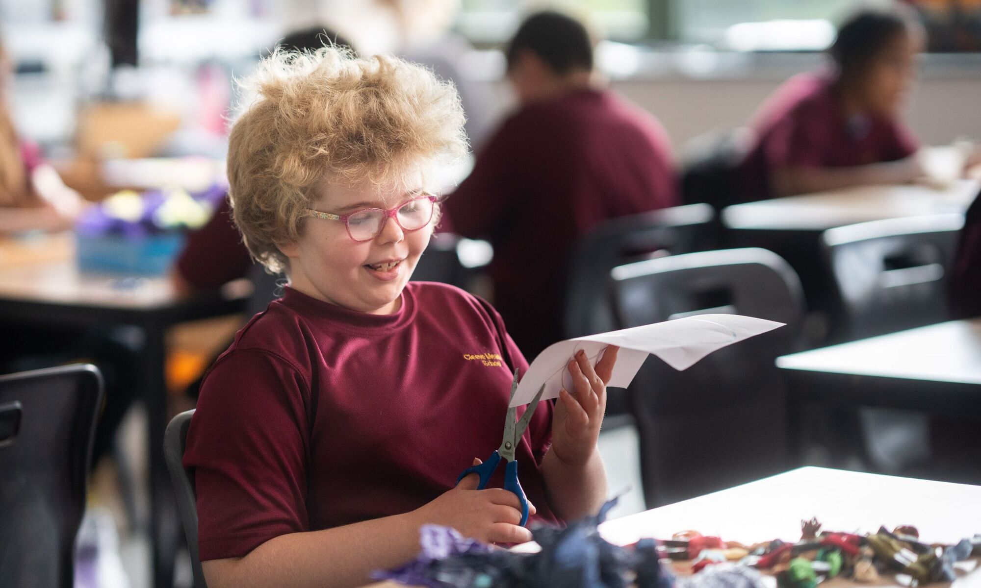 Female student cutting paper during art lesson